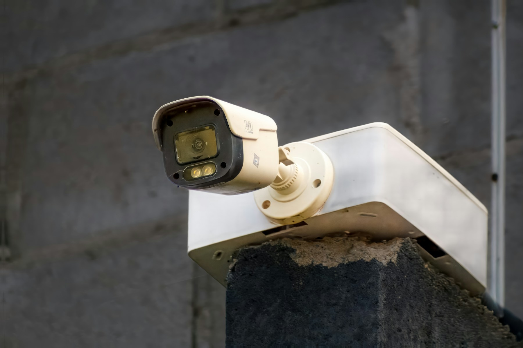 Outdoor bullet security camera mounted on a masonry pillar.